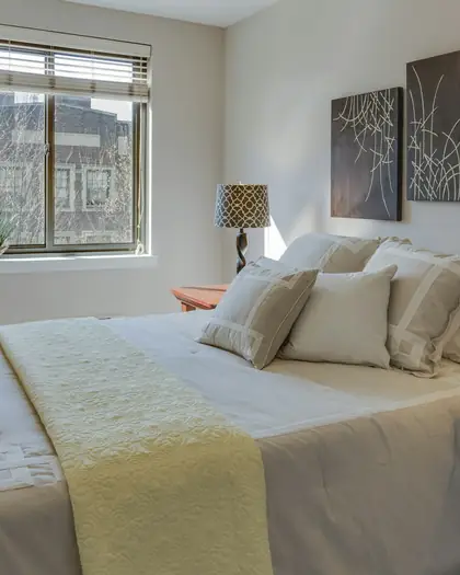 Made bed with cream pillows and a throw
